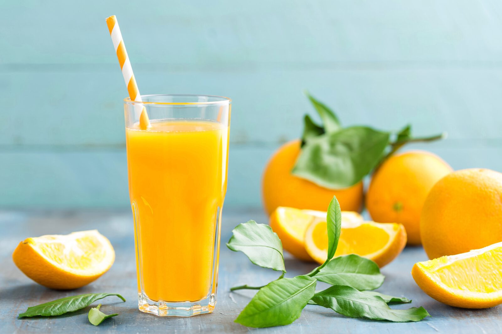 frischpresster Orangensaft im Glas, frische Orangen im Hintergrund auf Holz, vitamin drink